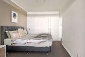 - une chambre avec un lit et une grande fenêtre dans l'établissement Luxury Apartment With Stunning Harbour & City View, à Auckland