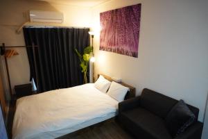 a bedroom with a white bed and a black chair at Crest YS Chiyoda 5A in Nagoya