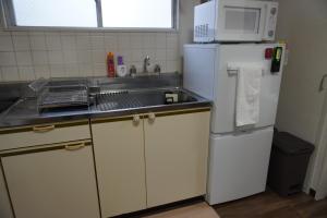 a kitchen with a white refrigerator and a microwave at Crest YS Chiyoda 5A in Nagoya