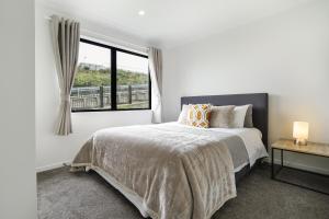 a white bedroom with a bed and a window at Stunning 3 bedrooms house in Hillcrest - Close to Waikato University & Cambridge in Hamilton