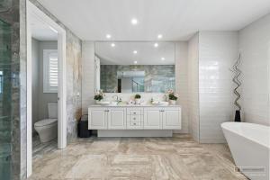 bagno con 2 lavandini, vasca e specchio di New Haven - Grand Canal View Suite a Banksia Beach