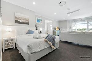 una camera da letto bianca con un letto grande e un divano di New Haven - Grand Canal View Suite a Banksia Beach
