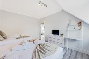 a white bedroom with two beds and a tv at Sweet and Lovely 2BR with Free Parking in London