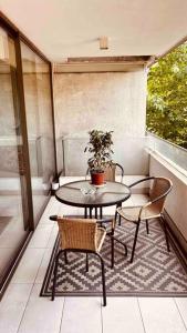uma mesa e cadeiras numa varanda com um vaso de plantas em Apartamento en Las Condes frente a parque araucano em Santiago