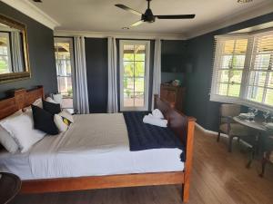 Schlafzimmer mit einem Bett, einem Tisch und Fenstern in der Unterkunft Blueberry Hill Vineyard Stay in Rothbury