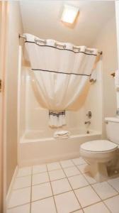 La salle de bains est pourvue de toilettes et d'une baignoire avec rideau de douche. dans l'établissement Branson King Resort, à Branson