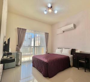 a bedroom with a bed and a desk and a window at Swallow Home in Hengchun South Gate