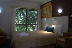um quarto com uma cama e uma grande janela em City Gardens Motel em Traralgon