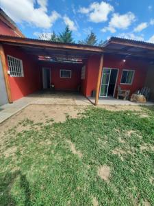 uma casa com uma casa vermelha com um quintal em Departamento con pileta anisacate los talas em Anisacate