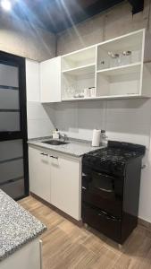 a kitchen with white cabinets and a black stove at Duplex alquiler Mar del Plata in Mar del Plata