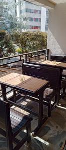 Hotel Palo Grande في مانيزاليس: مجموعة من الطاولات الخشبية والمقاعد على الشرفة