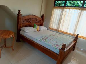 Schlafzimmer mit einem Holzbett, einem Tisch und Fenstern in der Unterkunft Nyoman House Ubud in Ubud