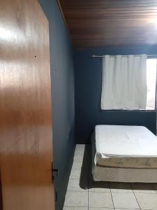 ein kleines Schlafzimmer mit einem Bett und einer Tür in der Unterkunft Casa Winter - Seu Quarto Ideal in Santa Rosa