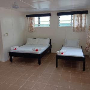 two beds in a room with two windows at Eco Dive Vanuatu Bungalows & Backpackers in Vitouara