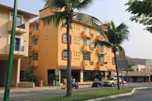 a large yellow building with palm trees in front of it at Casa Estrellas in Santa Maria Huatulco