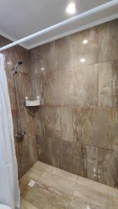 y baño con ducha y pared de piedra. en Cabaña 4-6 personas con piscina, en Algarrobo