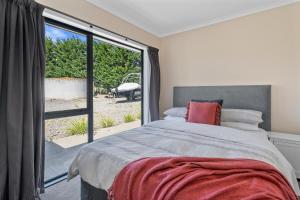 ein Schlafzimmer mit einem Bett und einem großen Fenster in der Unterkunft Meadowscape Hideaway - Martinborough Holiday Home in Martinborough 