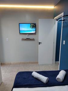 a bedroom with a bed and a flat screen tv on the wall at Suite Praia Parque in Penha