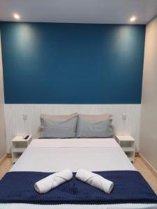 a bedroom with a large white bed with a blue wall at Suite Praia Parque in Penha