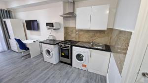 eine Küche mit einer Waschmaschine und einem Waschbecken in der Unterkunft Spacious 3-Bedroom Apartment - London in Wanstead