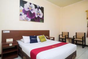 a hotel room with a bed and two chairs at UrbanView Hotel Anggraeni Jatibarang 