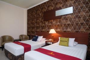 una camera d'albergo con due letti e una lampada di UrbanView Hotel Anggraeni Jatibarang 