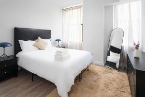 ein Schlafzimmer mit einem großen weißen Bett und einem Spiegel in der Unterkunft Luxury 2BD nr Wall St Gym Rooftop w/d in New York