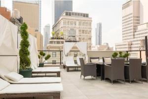 a rooftop patio with chairs and tables on a building at Luxury 2BD nr Wall St Gym Rooftop w/d in New York