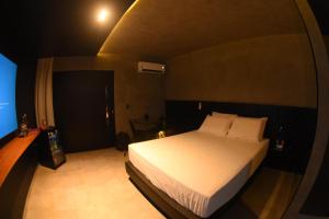 a bedroom with a white bed in a dark room at All in Motel in Garanhuns