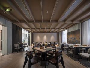MSW Hotel Changzhou في تشانغتشو: مطعم فيه طاولات وكراسي في الغرفة