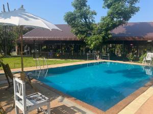 a large swimming pool with an umbrella and a chair at Chiang Mai Slowtime in Chiang Mai