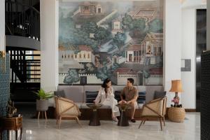 mężczyzna i kobieta siedzący na kanapie w holu w obiekcie Pranakorn Heritage Hotel w mieście Bangkok