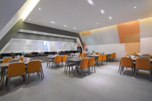 un comedor con mesas y sillas naranjas en Luzhou Baian Smart Hotel, en Luzhou