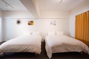 two beds sitting next to each other in a bedroom at Nagai park side stay in Osaka