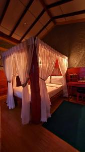 a bedroom with a canopy bed with white curtains at Guest Inn Avendra in Ella