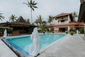 une statue d'une femme debout à côté d'une piscine dans l'établissement Bali Hai Island Resort, à Balian