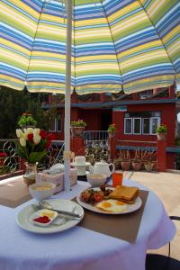 una mesa con platos de comida bajo una sombrilla en Sacred Trails Homestay, en Burhānilkantha