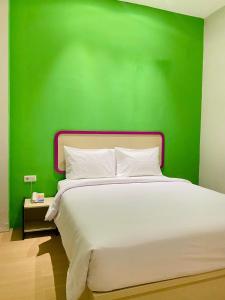 SukaramiにあるRuma Ruma Hotel Kenten - Palembangの緑の壁と白いベッドが備わるベッドルーム1室