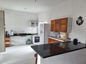 eine Küche mit weißen Geräten und einer schwarzen Arbeitsplatte in der Unterkunft Casa para temporada em caraguatatuba praia do Massaguaçu in Caraguatatuba