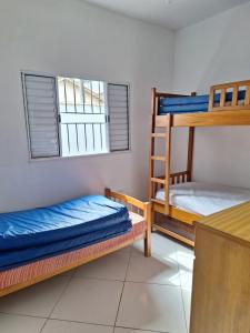 Zimmer mit 3 Etagenbetten und einer Theke in der Unterkunft Casa para temporada em caraguatatuba praia do Massaguaçu in Caraguatatuba