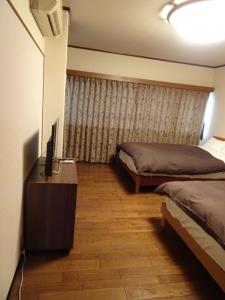 a bedroom with two beds and a television in it at Corpo Umeyama 2F / Vacation STAY 3912 in Mibu
