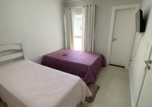 a small room with two beds and a window at Suíte Premium in Itajaí