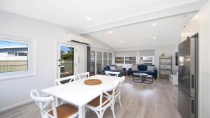 a dining room and living room with a white table and chairs at Ettalong Beach House in Ettalong Beach