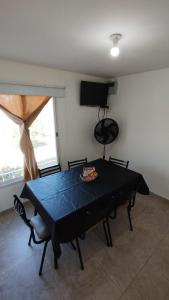 uma sala de jantar com uma mesa preta e uma televisão em El Roble, casa de sierra em Estancia Vieja