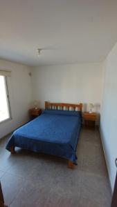 um quarto com uma cama azul com duas mesas de cabeceira em El Roble, casa de sierra em Estancia Vieja