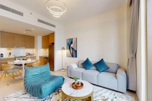 Summer at Creek Beach - Vacationer في دبي: غرفة معيشة مع أريكة زرقاء وطاولة