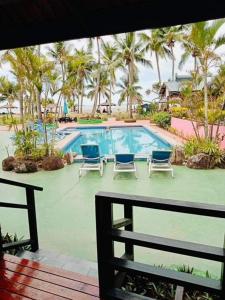 a view of a swimming pool with chairs and palm trees at Club Fiji Resort in Nadi