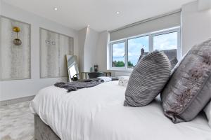 a bedroom with a white bed with pillows and a window at Contemporary 2 Bedroom Flat in Excellent Location! in London