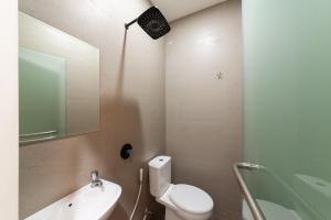 uma casa de banho com um WC, um lavatório e um espelho. em Urbanview Hotel Cengkareng Jakarta by RedDoorz em Jacarta