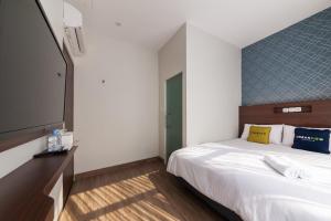 um quarto com uma cama e uma televisão de ecrã plano em Urbanview Hotel Cengkareng Jakarta by RedDoorz em Jacarta
